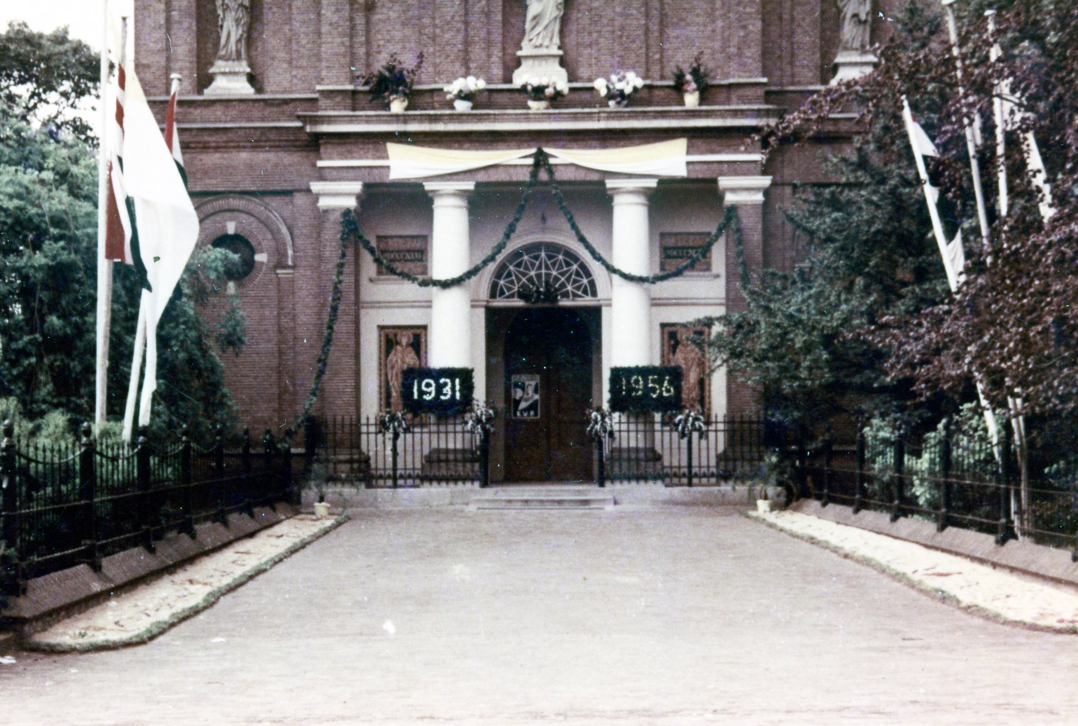 1956. Het kerkplein is versierd ter gelegenheid van het 25-jarig priesterjubileum van pastoor F. van de Berk (fotograaf onbekend)