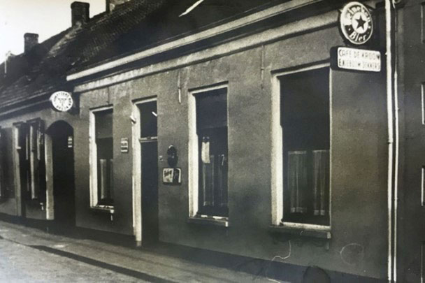 De buitenzijde van café De Kroon met de poort onder uithangbord van de Drie Hoefijzers, die via een gang - met zwaluwnesten tegen de balken van de zoldervloer - toegang tot eerst de feestzaal achter het café (collectie Albert Kieboom)