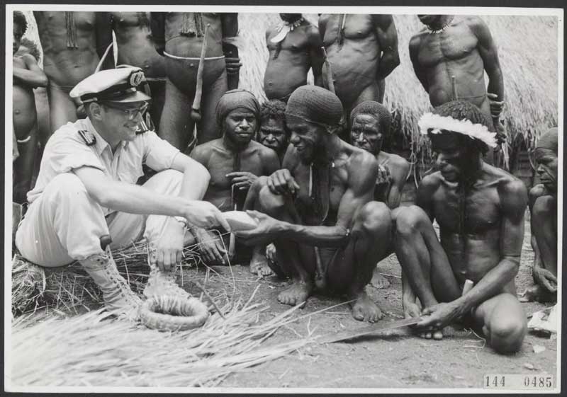 Aan de controleur B.B. mr. R.A. Gonsalves werd door een dorp een feestmaaltijd aangeboden. Als tegenprestatie werd het dorpshoofd een Meloschelp (in de Baliem kostbaarder dan een ijzeren bijl) en een rol inheemse tabak aangeboden, 1958 (foto: Kantoor voor Voorlichting en Radio Omroep Nieuw-Guinea. Bron: Nationaal Archief, fotonummer 2.24.05.02_144-0485. Publiek domein)