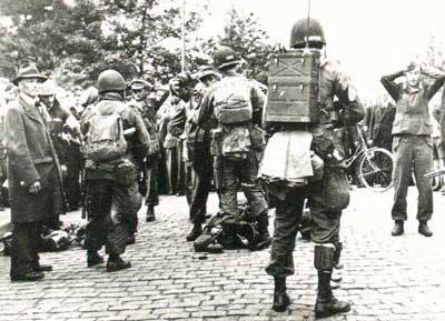 Amerikaanse paratroopers van de 101st Airborne Division fouilleren krijgsgevangen genomen Duitse Fallschirmjäger, 18 sept. 1944 (NIMH, fotonr. 2155_500384)