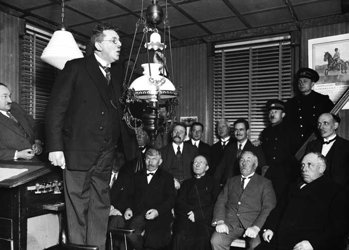 De burgemeester van Oijen blaast de laatste gemeentelijke petroleumlamp op het gemeentehuis uit, na de aansluiting op het elektrische net van de PNEM, 1930 (foto: Fotopersbureau Het Zuiden. BHIC, fotonr. 1651-000124)