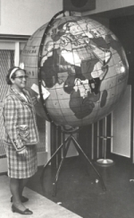 Anny Schafrat bij de wereldbol, waarop alle missiegebieden zijn aangegeven