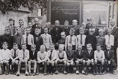 Op deze oude foto van de Rooise Jongensschool zie je Meester Oerlemans (zittend in het midden), Meester Van Rooij (staand rechts boven) en rechts naast Meester Oerlemans Piet Rovers.