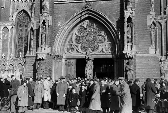 Deelnemers aan de emigratiecursus van de NCB verlaten de kerk in Veghel, maar dan na de mis (foto: Fotopersbureau Het Zuiden, 1951. Coll. BHIC, fotonr. 1673-006181)