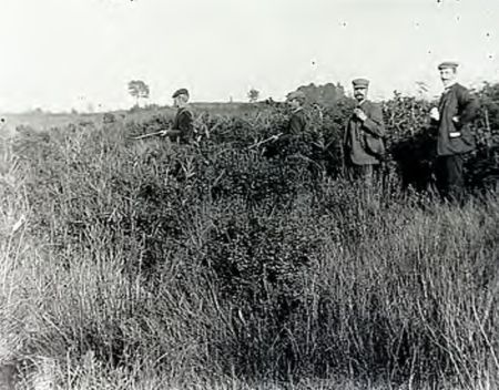 Vier jagers tussen het hoge gras, ca. 1910 (Foto: J.A. Baken, RHCe)